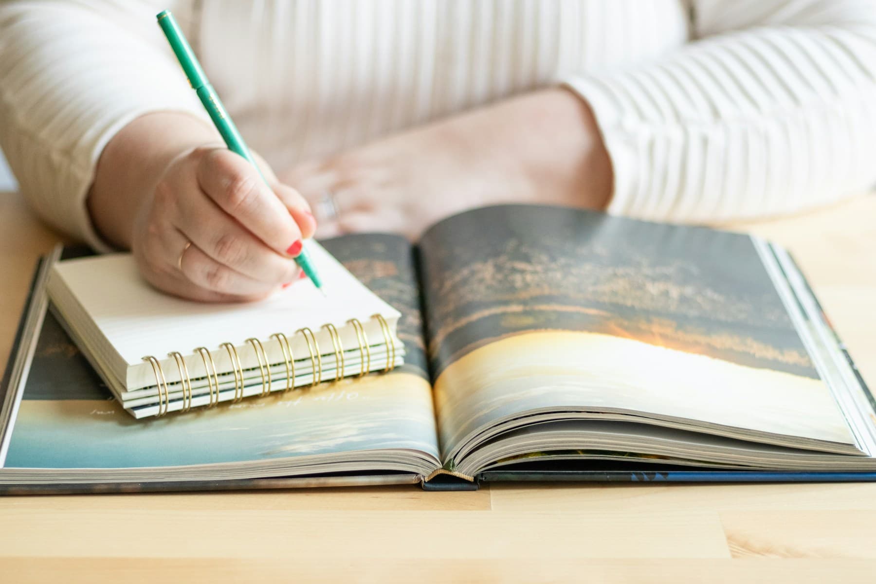 A person writing in a notebook with a pen