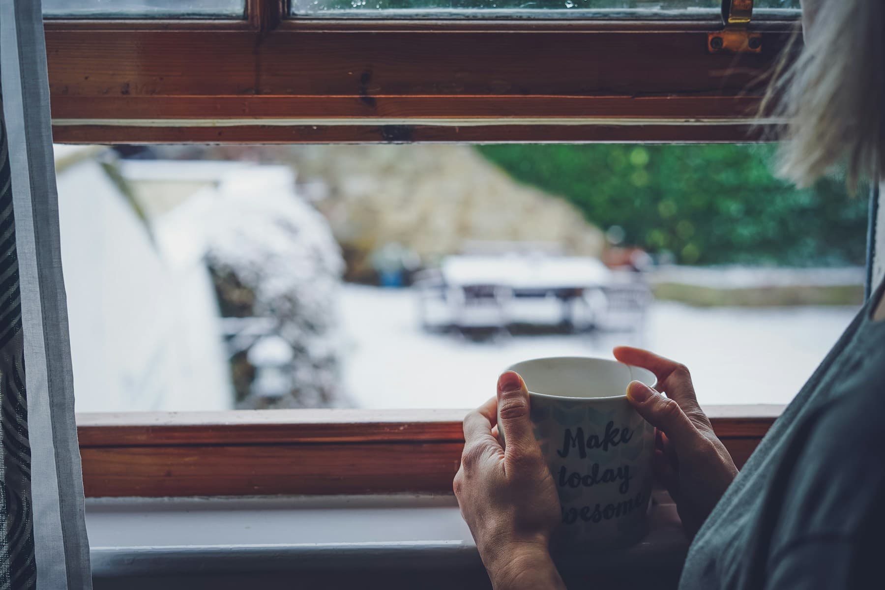 A person wrapped in a blanket holding a warm mug