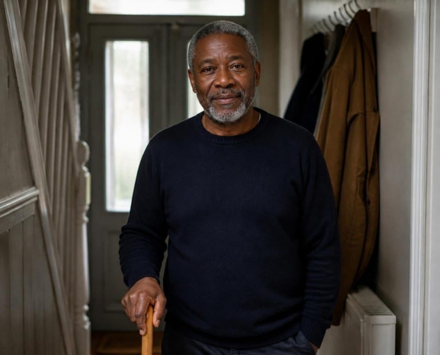 An older man standing in a hallway at home, looking relaxed