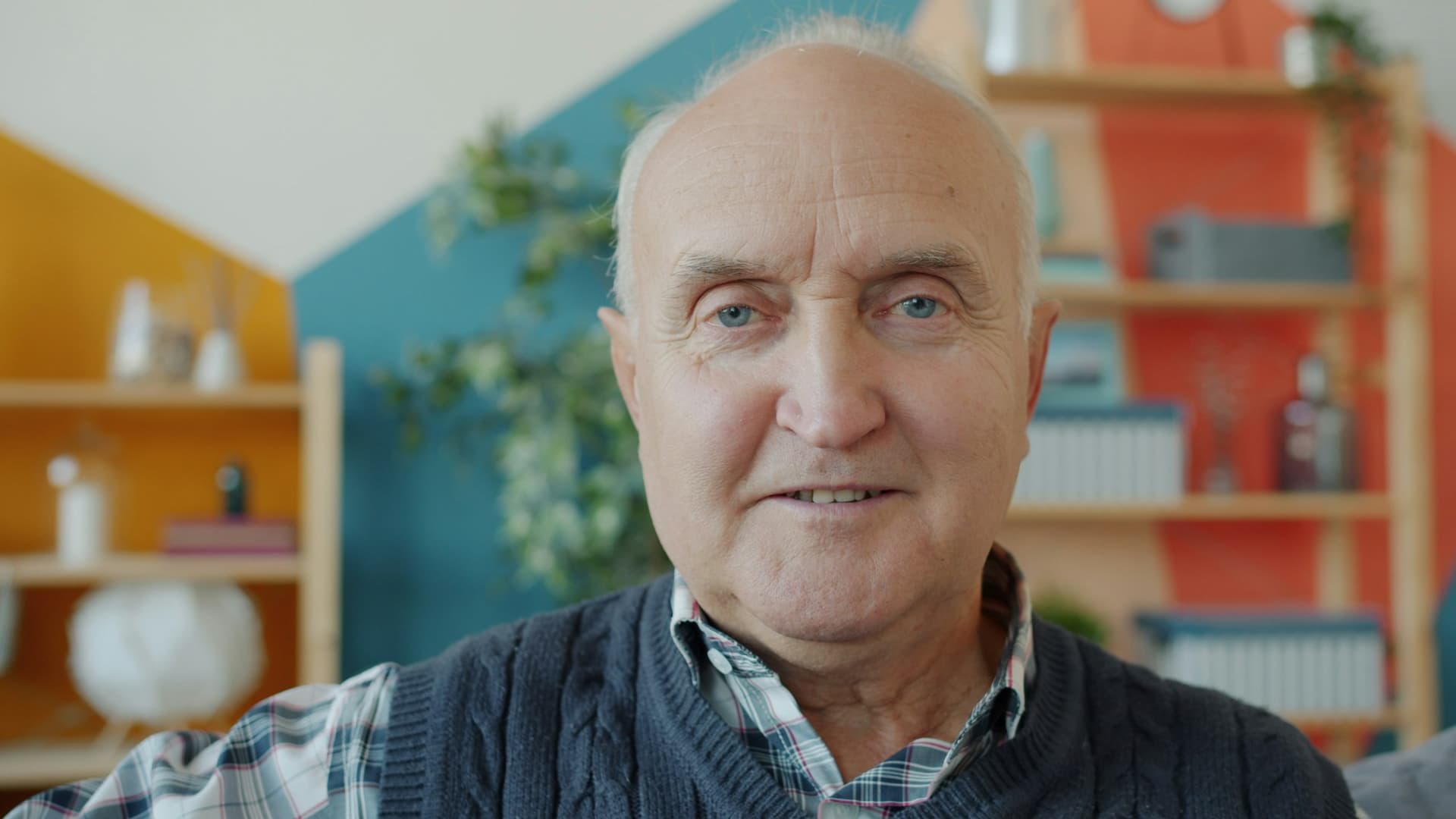 An older man with a warm smile sitting in his living room