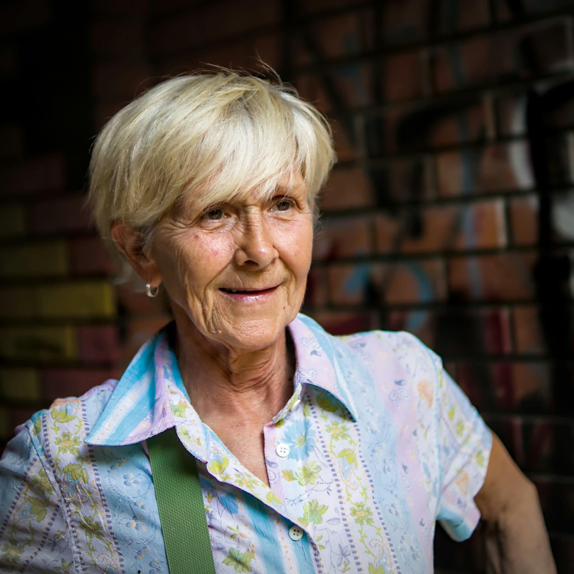 An older woman with short white hair smiling warmly in the sunshine