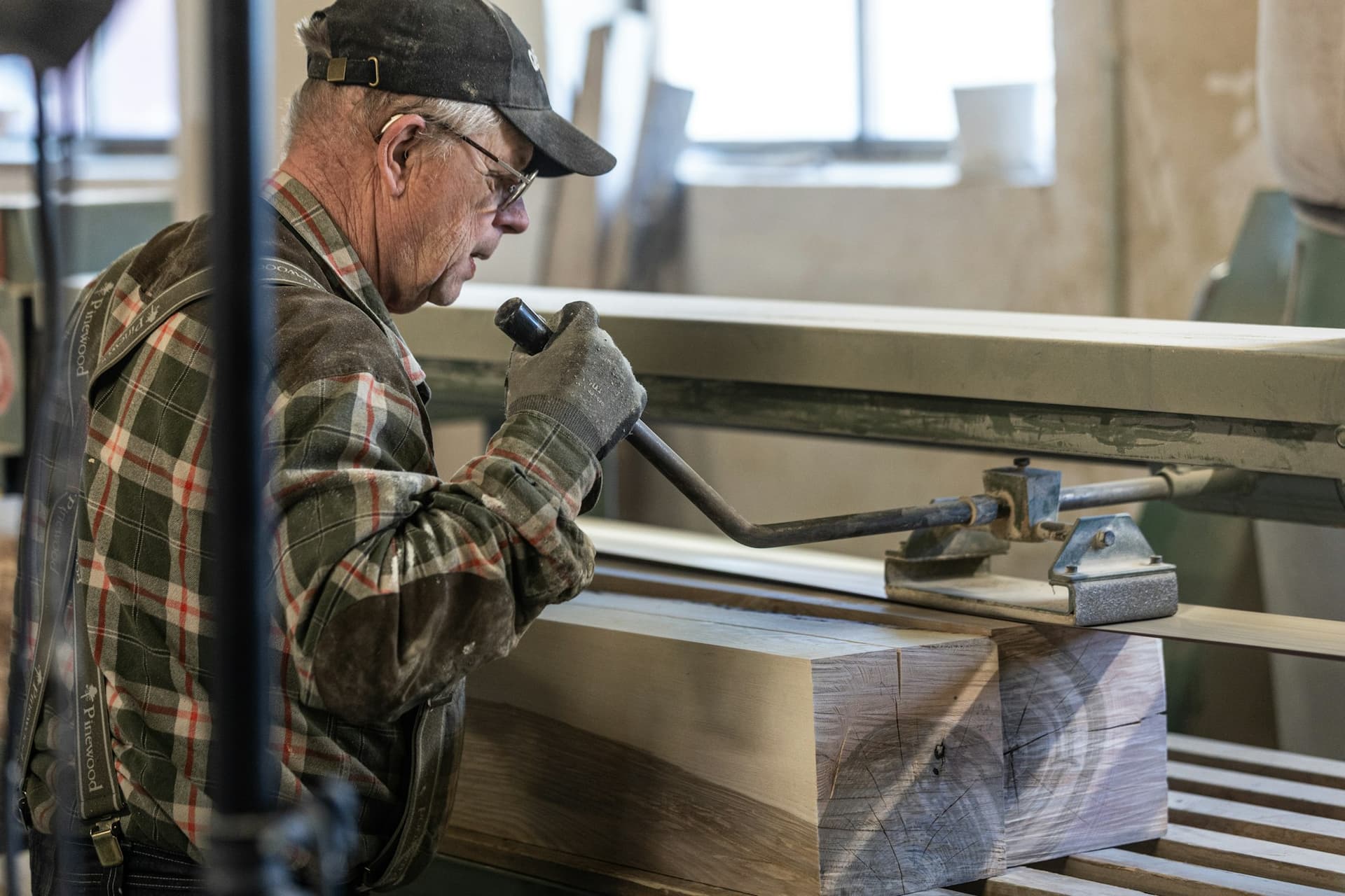 A man in a flat cap sanding timber in a community workshop